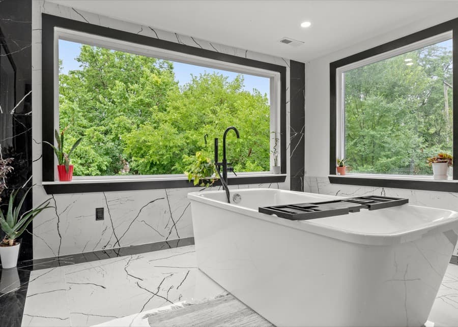 White bathroom with a freestanding tub under a large window
